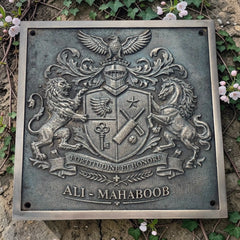 Bronze metal plaque with a coat of arms and 'ALI MAHABOOB' text, surrounded by greenery.