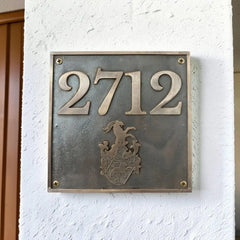 Meta house number plate with '2712' and a coat of arms on a white wall.
