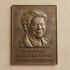 Bronze plaque with a portrait and engraved text on a beige wall