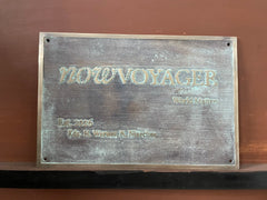 Bronze plaque with 'NOWVOYAGER' branding on a brown background