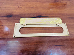 Brass letter opener with yellow handle on a wooden surface