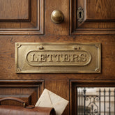 Brass letterplate on a wooden door with an envelope underneath