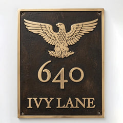 Bronze or brass address plaque featuring a cast eagle emblem above the house number and street name.