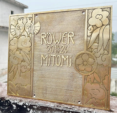 Decorative metal plaque with engraved designs and text on a wooden surface.