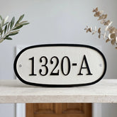 Personalized cast bronze address sign with raised letters House number sign '1320-A' on a white background with decorative elements.