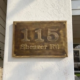 Bronze house number plaque on a white wall