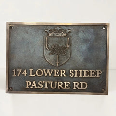 Bronze metal sign with emblem and text on a white background