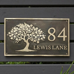 Decorative house number sign with tree design on a wooden background - handcrafted bronze house number plaque