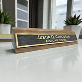 Personalized brass desk name plate with wooden base on a desk in an office setting