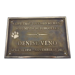 Bronze plaque with engraved text and paw print on a white background