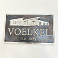 Bronze sign with house silhouette and 'VOELKEL Est. 2025' text on a white background
