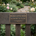 Bronze plaque with engraved text on a wooden post in a garden setting
