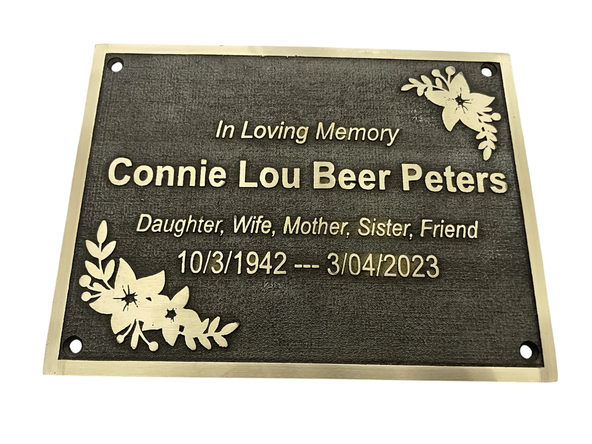 Memorial plaque with engraved text and floral designs on a white background