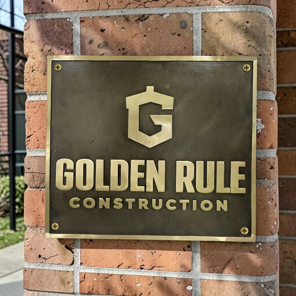 Bronze sign with 'Golden Rule Construction' logo on a white background