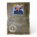 Bronze plaque with engraved text and a photo of a man, on a white background