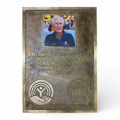Bronze plaque with engraved text and a photo of a man, on a white background