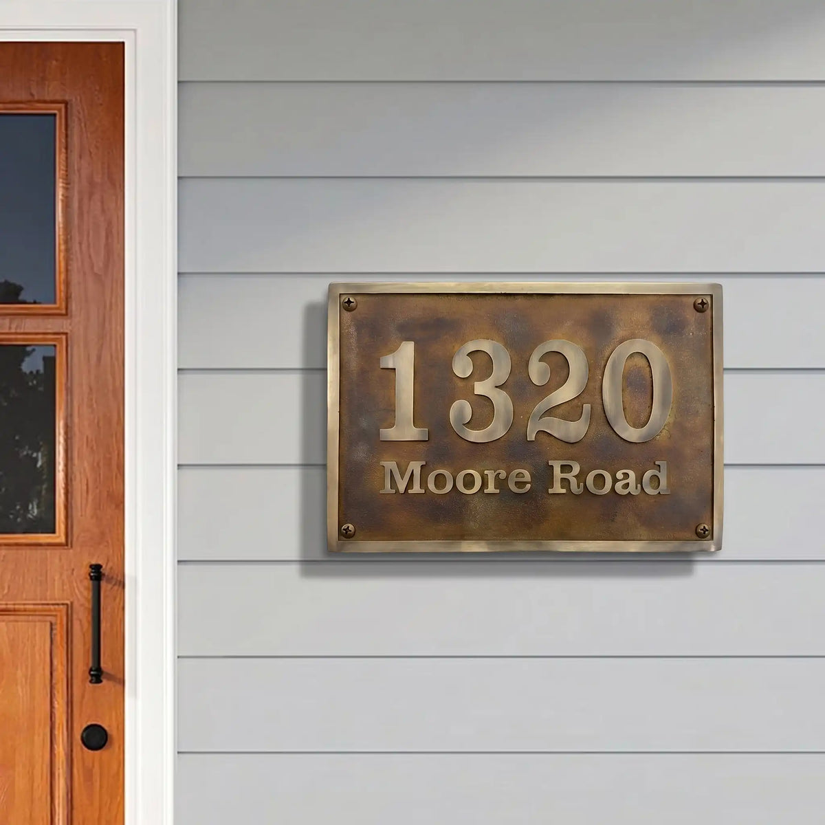 House number sign '1320 Moore Road' on a gray wall next to a wooden door.