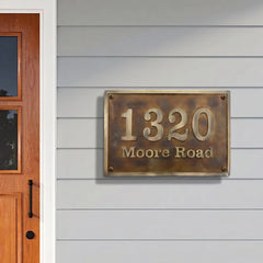 House number sign '1320 Moore Road' on a gray wall next to a wooden door.