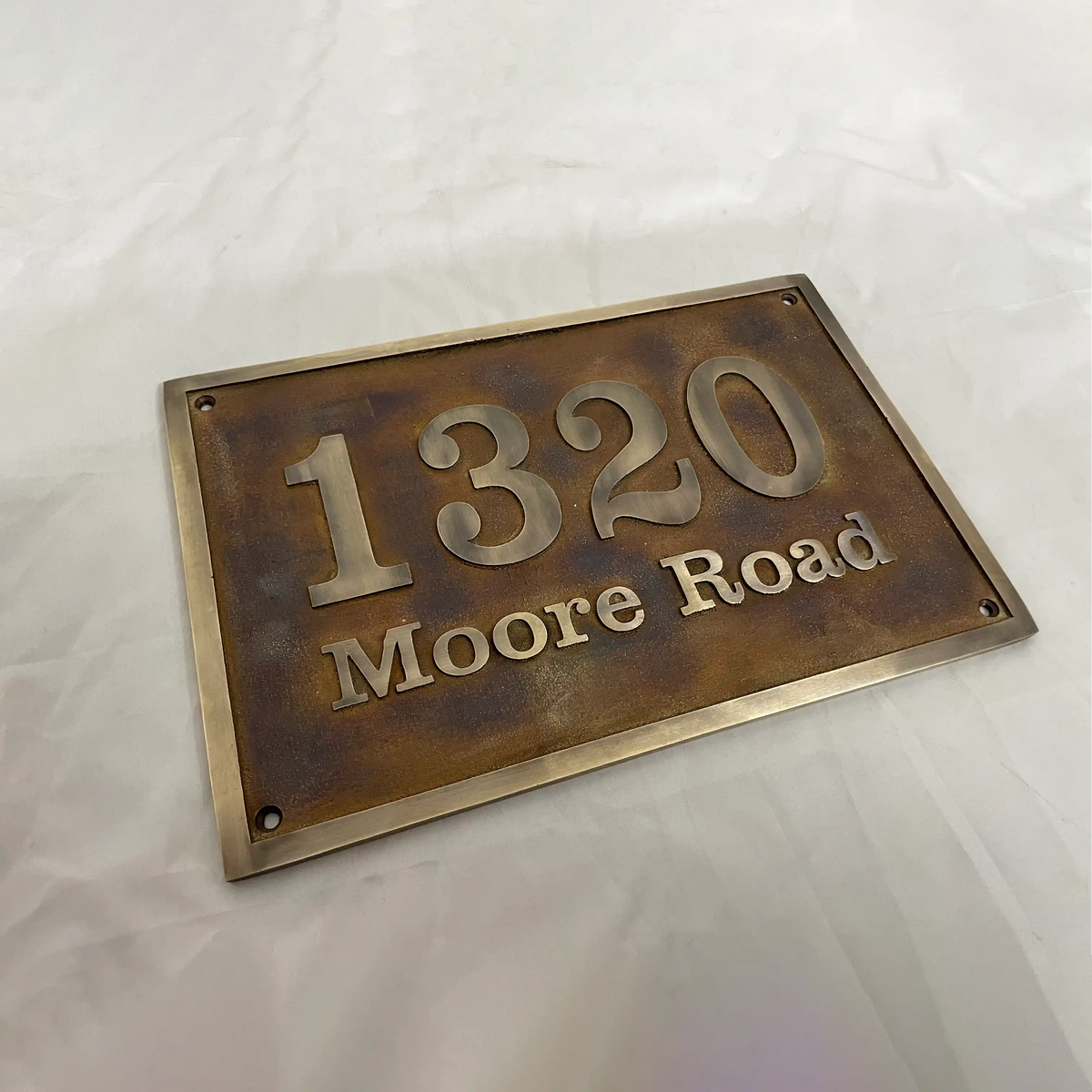Bronze house number sign with '1320 Moore Road' on a white background