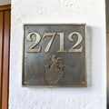 Meta house number plate with '2712' and a coat of arms on a white wall.