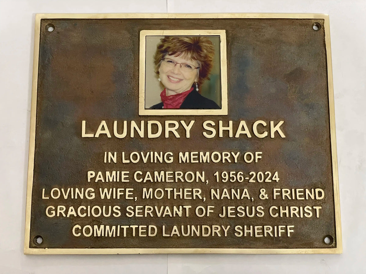Bronze memorial plaque with a portrait and raised gold lettering