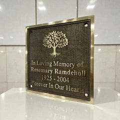 Memorial plaque with tree design and engraved text on a reflective surface.