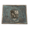 Bronze plaque with a bear emblem, trees, and 'Est. 1929' text on a white background