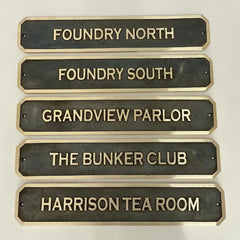 Set of bronze nameplates with gold text on a white background