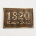 Bronze house number sign with '1320 Moore Road' on a white background
