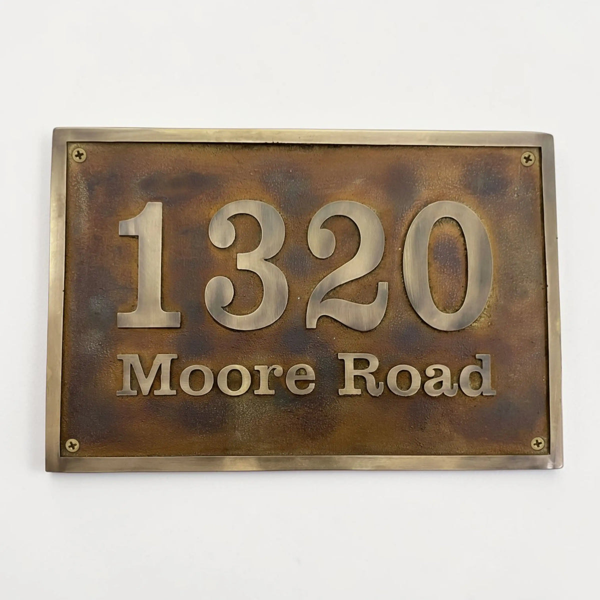 Bronze house number sign with '1320 Moore Road' on a white background