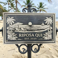 Bronze address sign with beach scene and 'Riposa Qui' text on a beach background