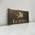 Custom Bronze sign with 'Ca' D'Oro' and a lion emblem on a white surface.