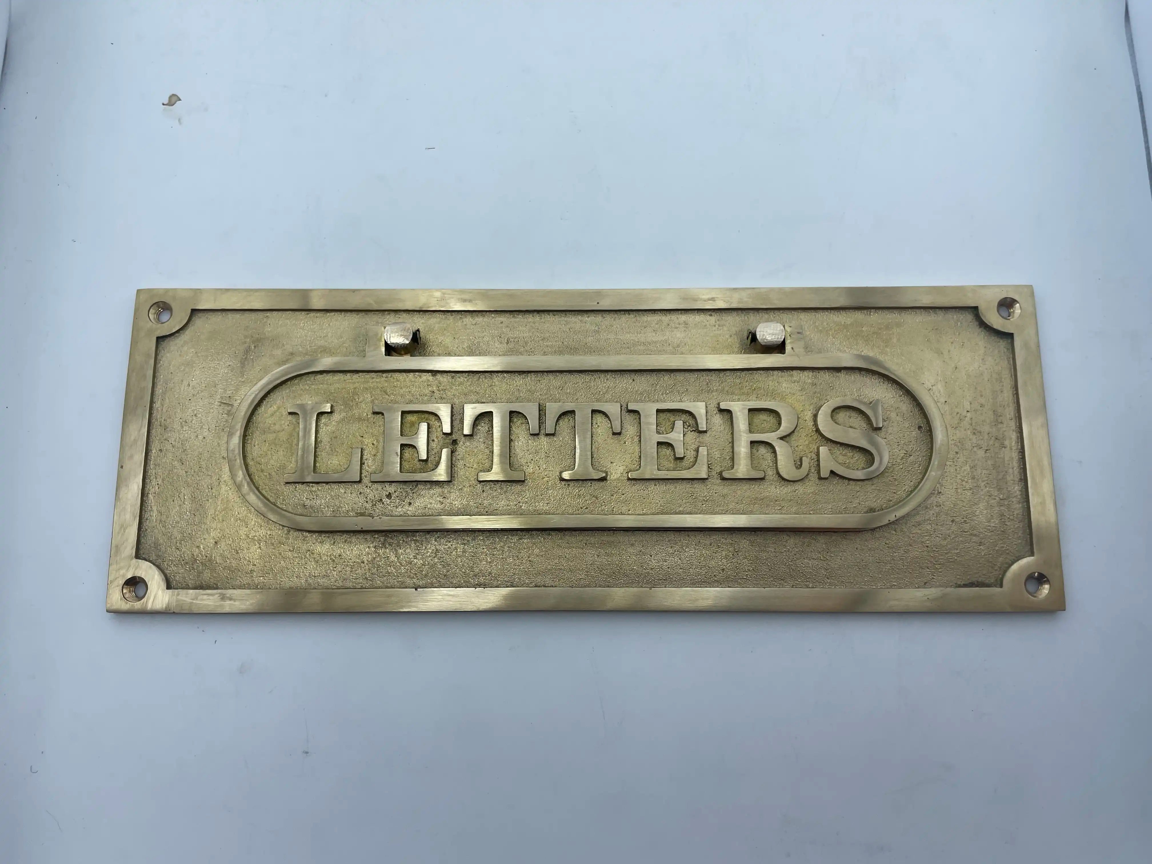 Brass letter box plate with 'LETTERS' engraved on a light gray background