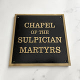Custom Bronze Sign with 'Chapel of the Sulpician Martyrs' text on a black background with gold lettering.
