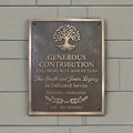 Decorative plaque with tree design and engraved text on a gray wall.