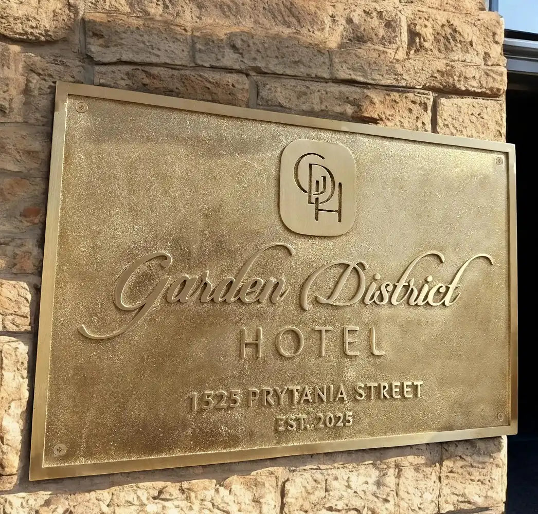 Bronze plaque on a stone wall for Garden District Hotel