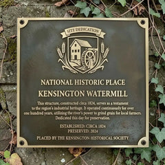 Plaque commemorating the Kensington Watermill, a National Historic Place, on a stone wall with ivy.