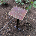 Memorial plaque for Astrid Artho in a garden setting with a small tree.