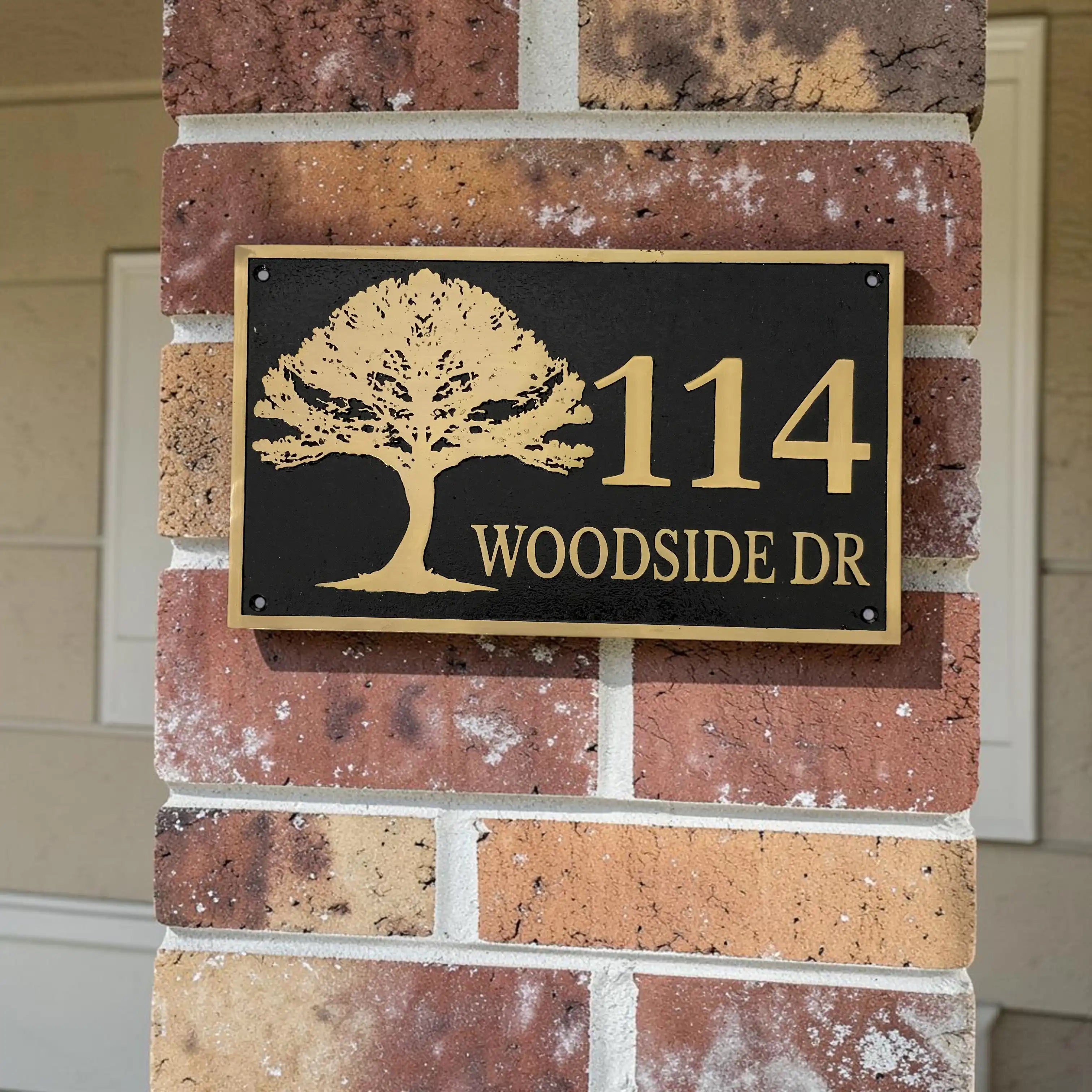 House number sign with tree design on a brick wall