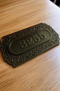 Decorative house number plate with '3255' on a wooden surface