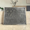 Memorial plaque for a dog named Scout's Swamp with engraved text on a wooden surface.