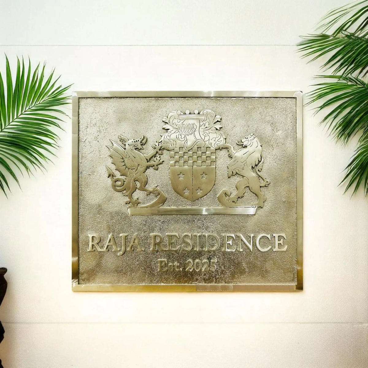 Decorative plaque with 'Raja Residence' on a wall with green leaves.