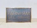 Metal sign with 'Farnham Eye Care' text on a white background