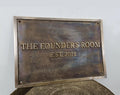 Bronze plaque with 'The Founder's Room EST. 2011' text on a gray background