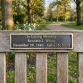 Bench Memorial plaque for Kenneth L. White in a park setting with trees and flowers.