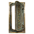 Brass mail slot for door installed on wooden front door exterior