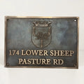 Bronze metal sign with emblem and text on a white background