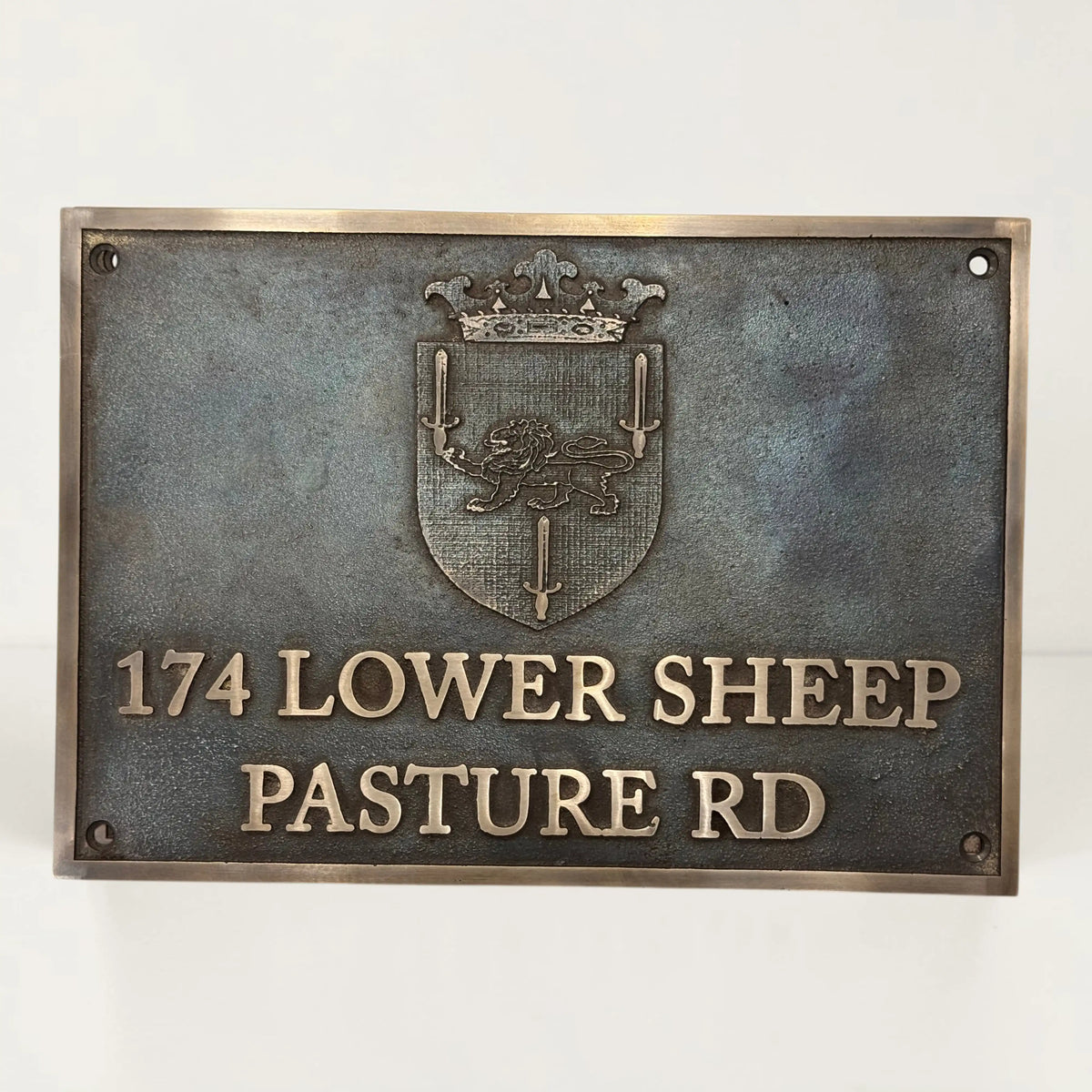 Bronze metal sign with emblem and text on a white background