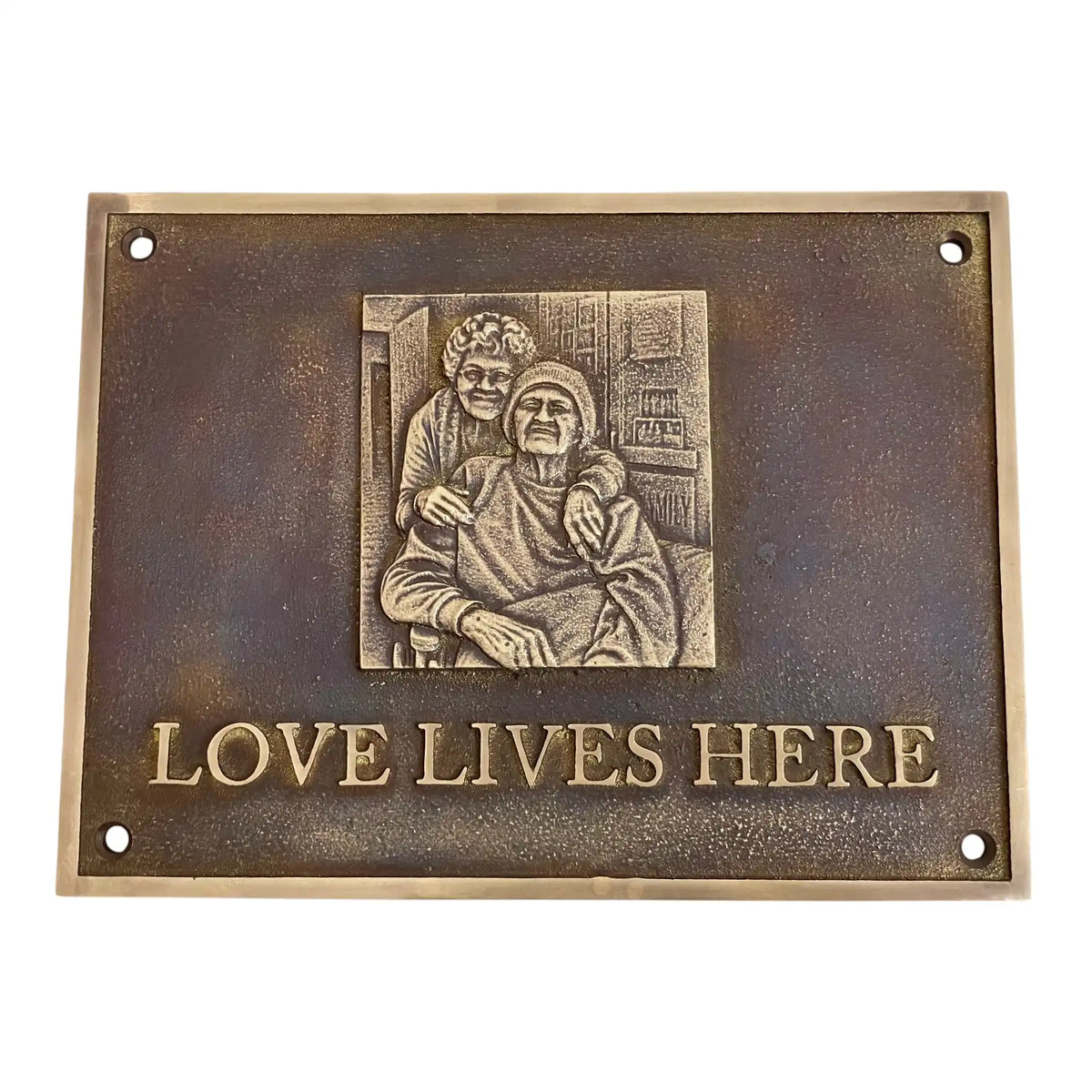 Bronze plaque with an engraving of two people and 'Love Lives Here' text on a white background
