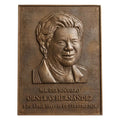 Bronze plaque with a portrait and engraved text on a white background